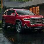 A red 2020 GMC Acadia is parked in front of a modern house.