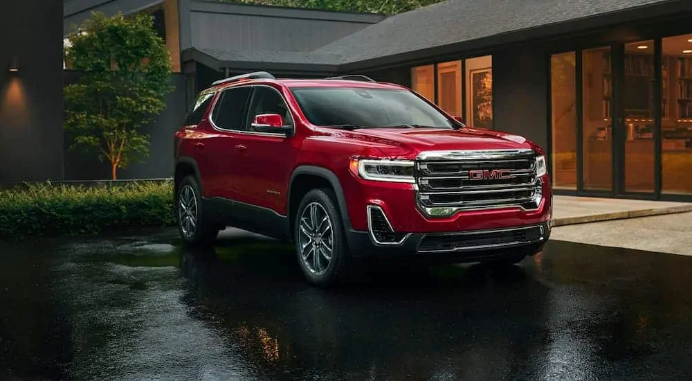 A red 2020 GMC Acadia is parked in front of a modern house.