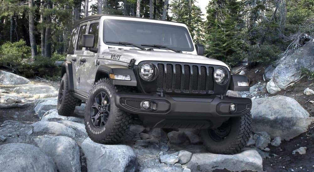 A silver 2020 Jeep Wrangler Unlimited Willy's Edition from a Jeep dealer near me is crawling over rocks, shown from the front.