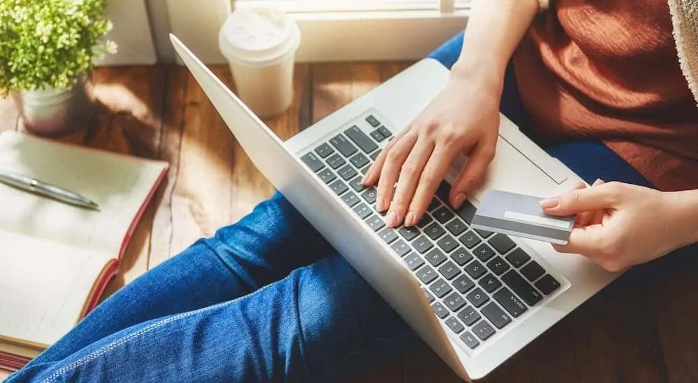 A woman is on her laptop doing some online car shopping.