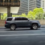 A gray 2020 Chevy Tahoe is driving in a city and shown from the side.