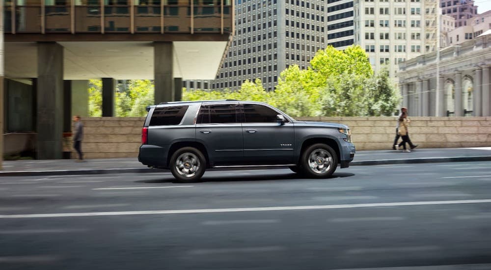 A gray 2020 Chevy Tahoe is driving in a city and shown from the side.