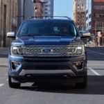 A blue 2020 Ford Expedition Platinum is shown from the front driving on a city street.