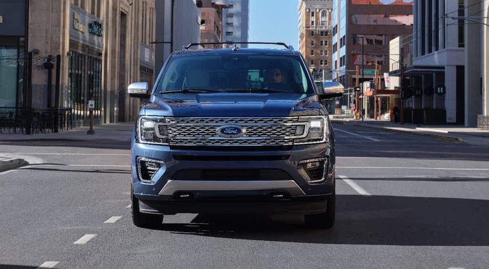 A blue 2020 Ford Expedition Platinum is shown from the front driving on a city street.