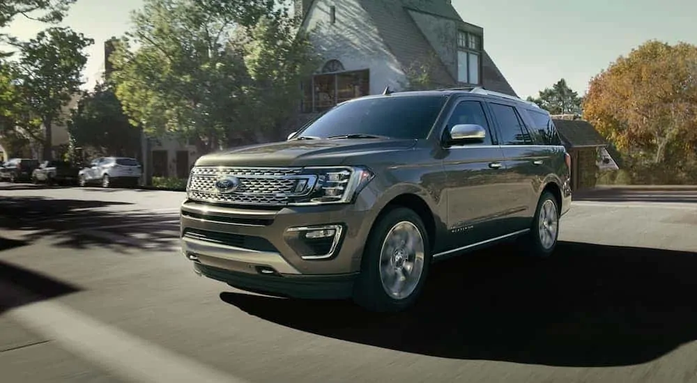 A gray 2020 Ford Expedition Platinum is driving on a suburban street.