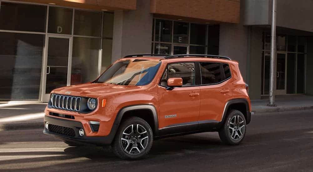 An orange 2020 Jeep Renegade is parked on a city street.