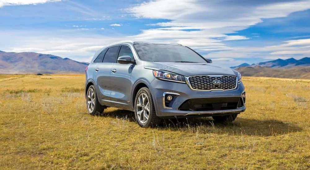 A grey 2020 Kia Sorento is parked in a field with mountains in the distance after winning the 2020 Kia Sorento vs 2020 Honda Pilot comparison.