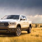 A white 2020 Ram 1500 is parked in an open field.