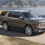 A grey 2021 Chevy Tahoe is driving past a body of water after winning the 2021 Chevy Tahoe vs 2020 Chevy Tahoe comparison.