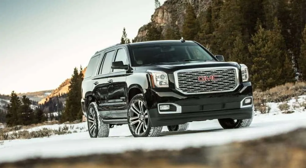 A black 2020 GMC Yukon Denali is parked on a snowy road.