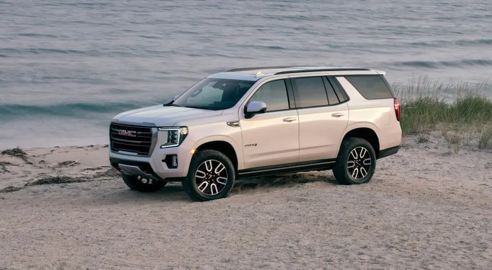 A white 2021 GMC Yukon AT4 is parked at a beach after showing the new trim available on the 2021 GMC Yukon vs 2020 GMC Yukon.