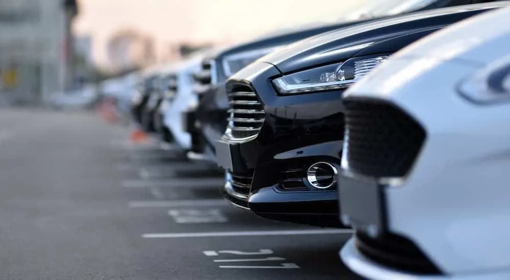 A closeup shows a row of used cars.