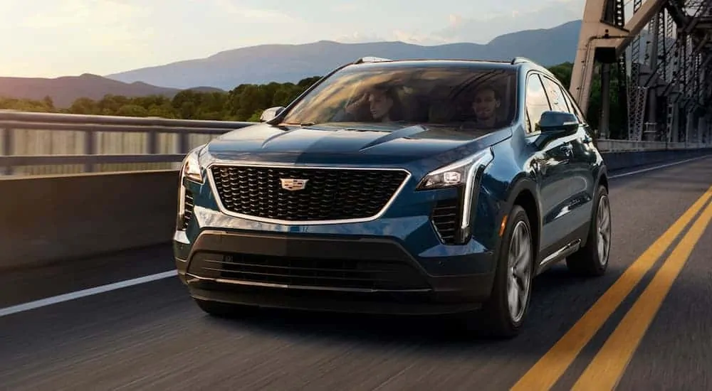 A blue 2020 Cadillac XT4 is driving over a bridge.