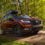 A red 2020 Honda Passport AWD Elite from a local Honda Dealer is driving on a woodland trail near Newnan, GA.