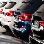 SUVs and cars are parked in a row at a local used car dealership.