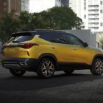 One of the new Kia models for the year, a yellow 2021 Kia Seltos, is parked in a city.