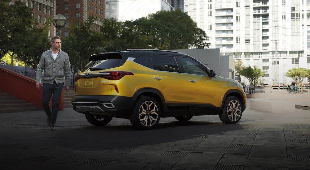 One of the new Kia models for the year, a yellow 2021 Kia Seltos, is parked in a city.
