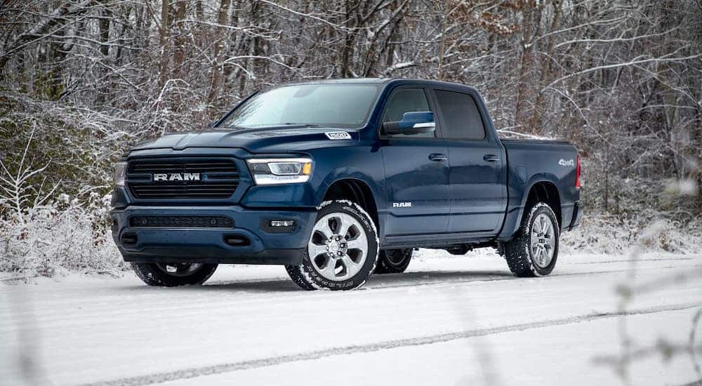 A popular Ram truck special edition, a blue 2020 Ram 1500 is parked on a snowy woodland road.