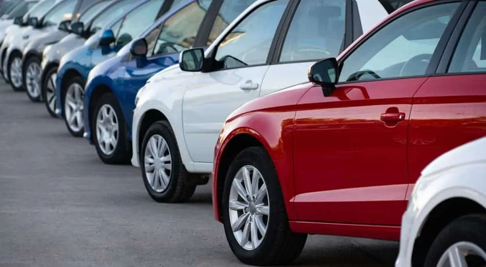 A row of different colored used cars for sale is shown.
