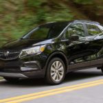 A black 2020 Buick Encore is driving past trees after winning the 2020 Buick Encore vs 2020 Chevy Trax comparison.