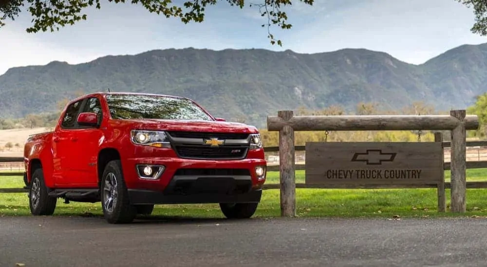 A white 2020 Chevy Colorado is parked in front of a fence and sign that reads 'Chevy Truck Country.'