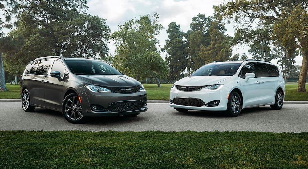 A gray 2020 Chrysler Pacifica and a white 2020 Chrysler Pacifica Hybrid are parked in a park.