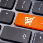 A closeup of a black keyboard is shown and one of the keys is replaced with an orange shopping cart button.