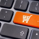 A closeup of a black keyboard is shown and one of the keys is replaced with an orange shopping cart button.