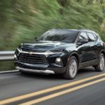 A green 2020 Chevy Blazer is driving on a rural highway.