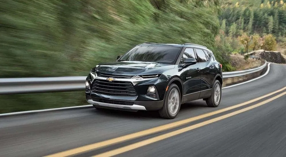A green 2020 Chevy Blazer is driving on a rural highway.