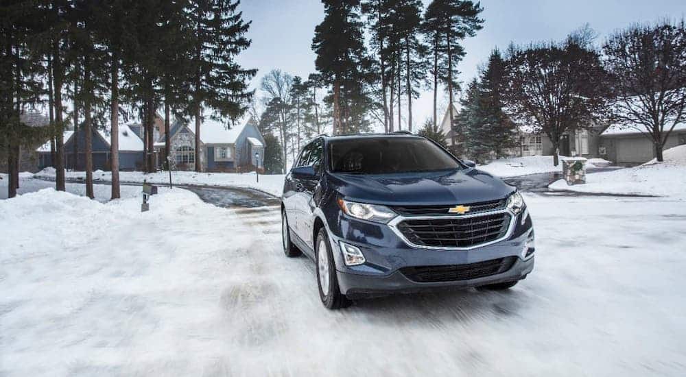 A dark blue 2020 Chevy Equinox is driving on a snowy road.