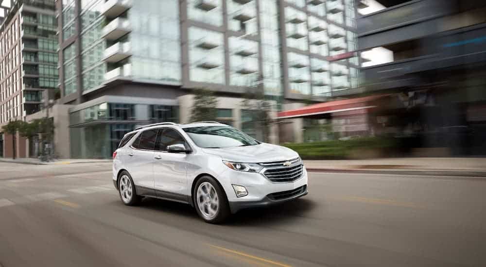 A white 2020 Chevy Equinox is driving on a city street.