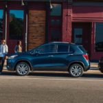 A couple is walking towards a parked blue 2020 Chevy Trax.