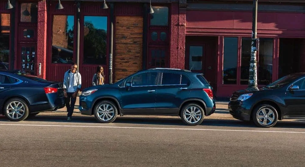 A couple is walking towards a parked blue 2020 Chevy Trax.