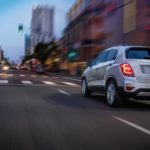 A white 2020 Chevy Trax is driving on a city street.