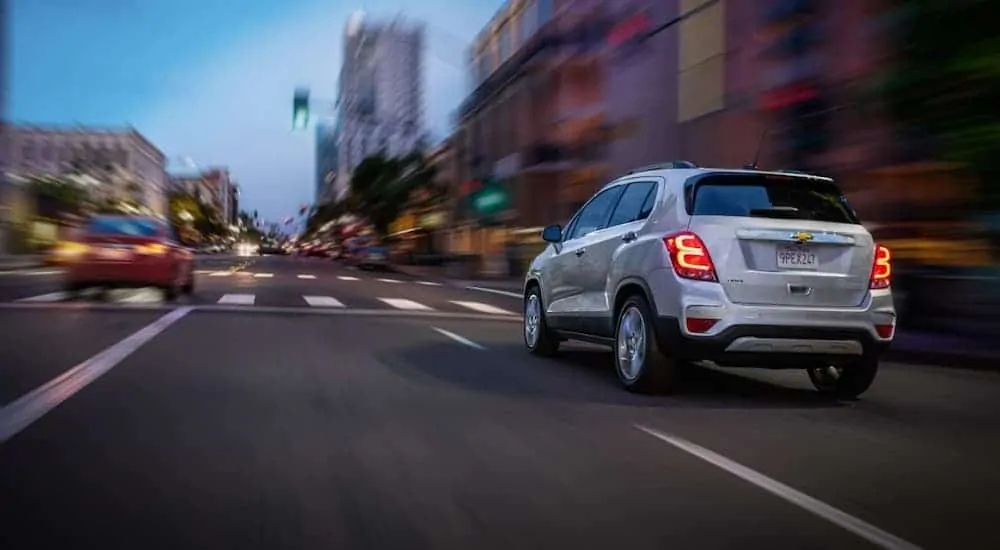 A white 2020 Chevy Trax is driving on a city street.