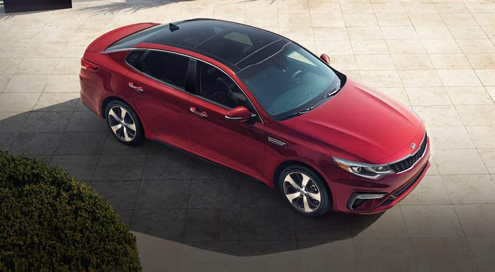 A red 2020 Kia Optima is shown from above on tan tiles after winning the 2020 Kia Optima vs 2020 Toyota Camry comparison.