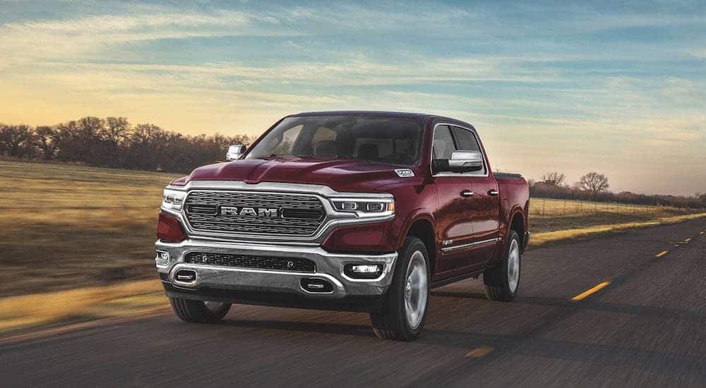 A red 2020 Ram 1500 is driving on a highway through a field.