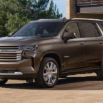 A brown 2021 Chevy Tahoe is parked in front of a garage.