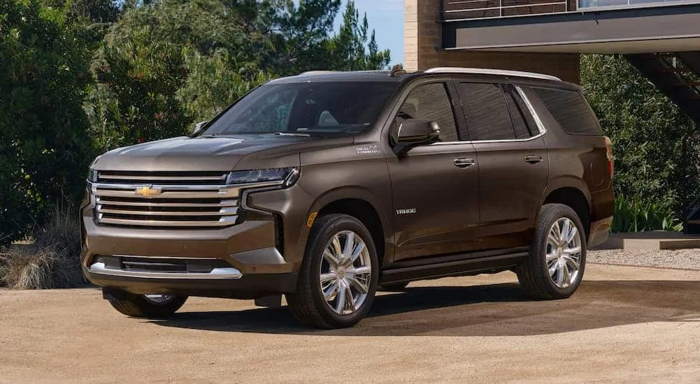 A brown 2021 Chevy Tahoe is parked in front of a garage.