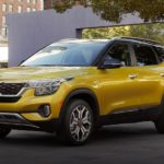 A yellow 2021 Kia Seltos is parked in a city park.