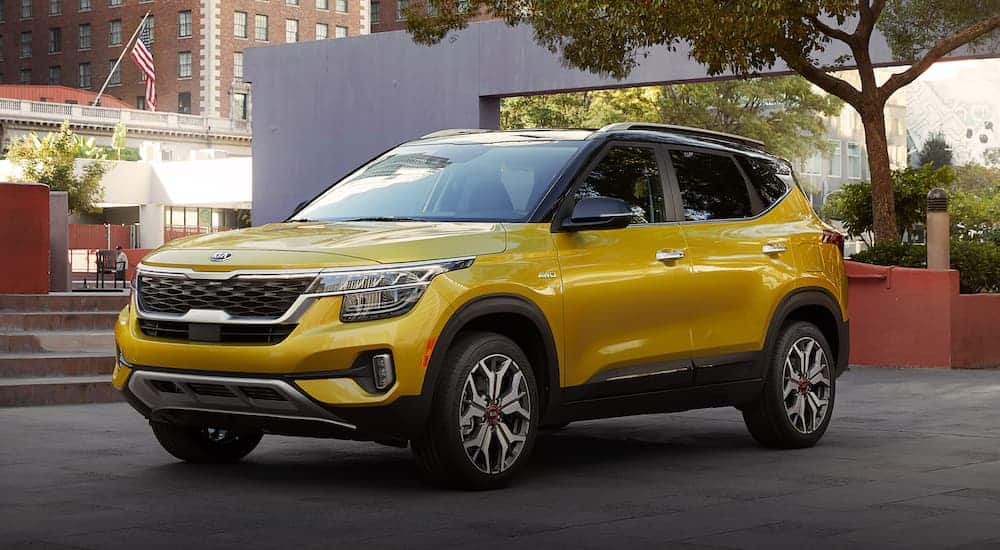 A yellow 2021 Kia Seltos is parked in a city park.