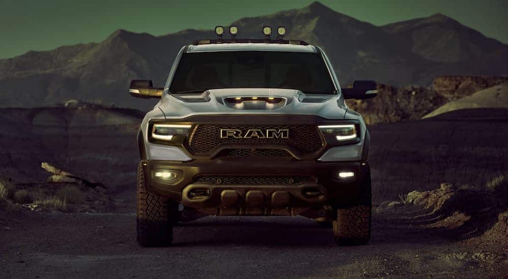 A silver 2021 Ram 1500 TRX is facing forward at dusk in front of mountains.