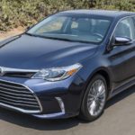 A blue 2017 Toyota Avalon from your local used car dealership is driving on a desert highway.