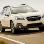 A white 2019 Subaru Outback, a popular used car, is driving on a desert road.