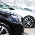 Used vehicles for sale are parked in a row in a bright dealership.