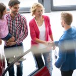 A family is meeting a car salesman to look at used vehicles for sale.
