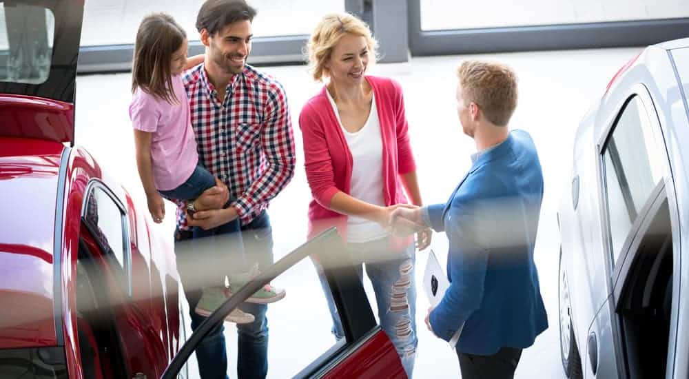 A family is meeting a car salesman to look at used vehicles for sale.