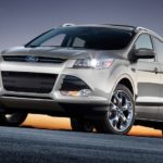 A silver 2013 used Ford Escape is parked with the sun rising behind it.