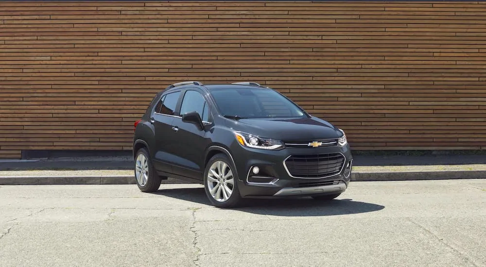 A dark blue 2020 Chevy Trax is parked in front of a wooden wall as part of the 2020 Chevy Trax vs 2020 Buick Encore comaprison.